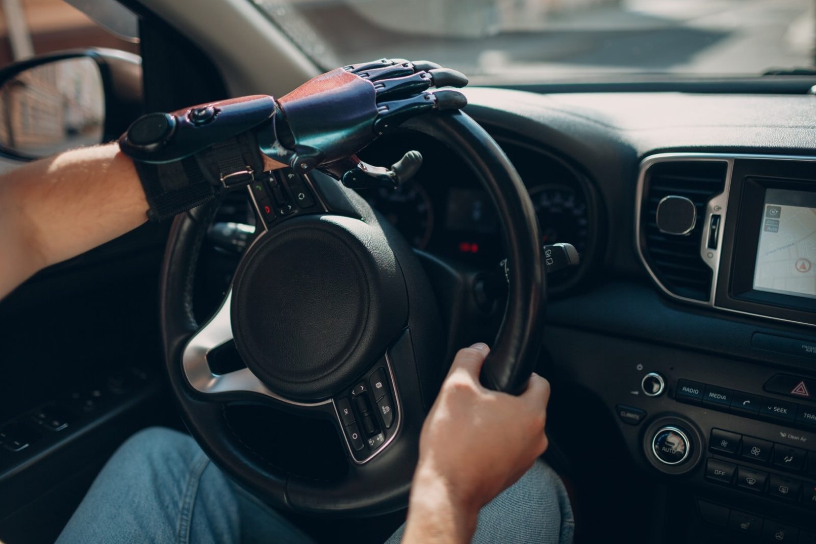 Young disabled man driver with artificial prosthetic hand driving on steering wheel vehicle car
