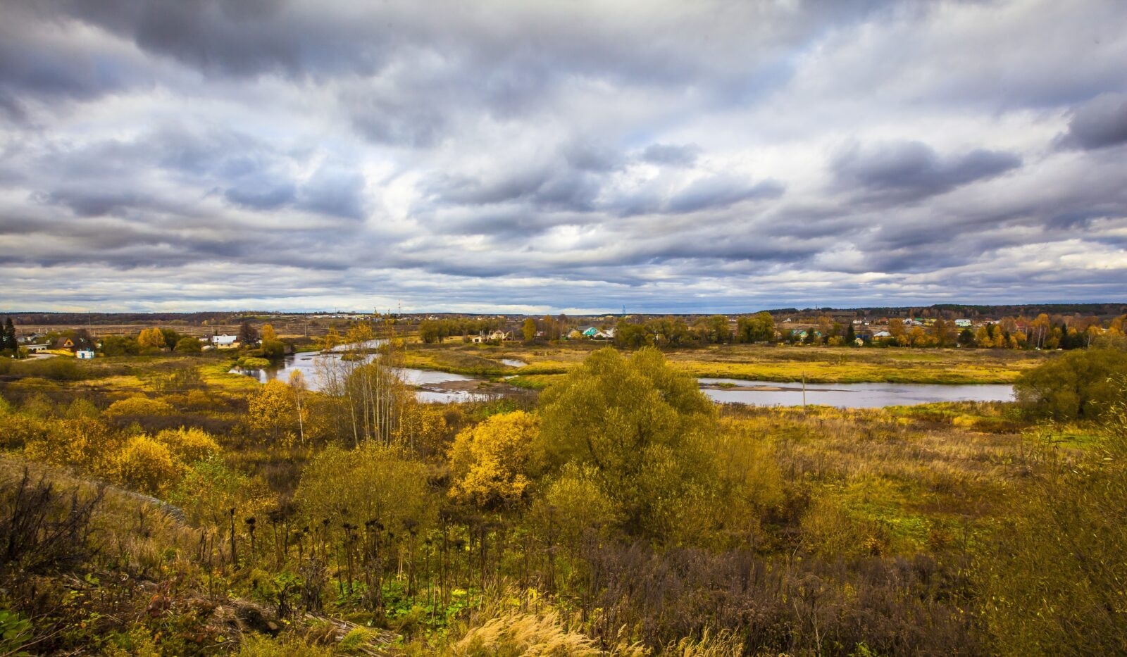 A beautiful village in Russia in autumn, with the the beautiful yellow trees under the cloudy sky